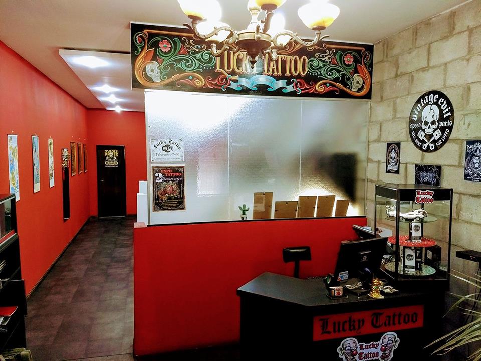 Recepción del estudio LUCKY TATTOO en Ituzaingó con cartel pintado a mano y ambientación vintage roja y dorada